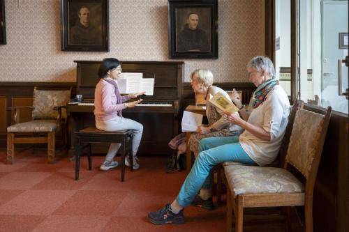 Organiste Naoko neemt de liederen door met Gré en Gitta